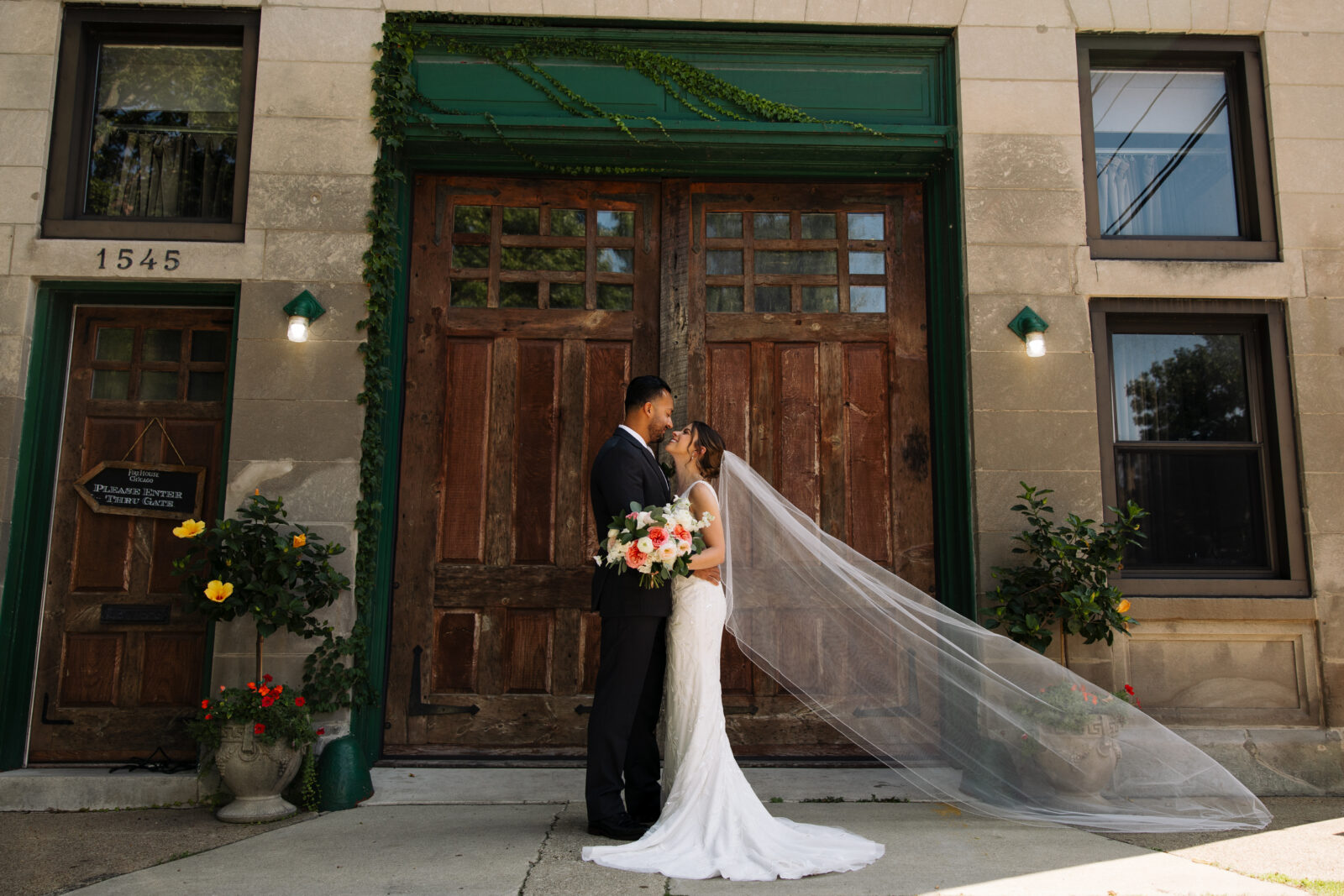 Bride and Groom with beautiful veil shot and stunning florals in front of The Firehouse Chicago.