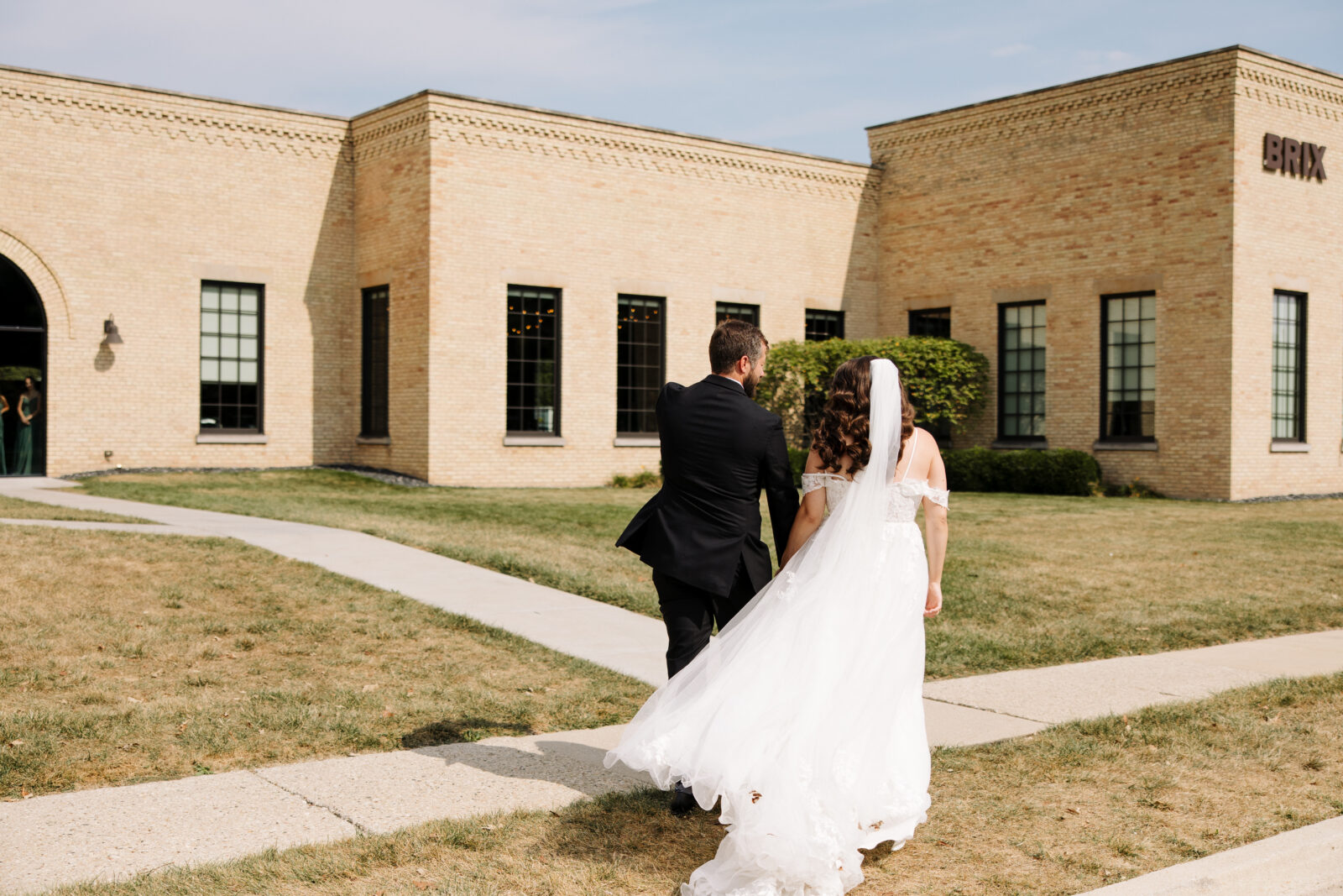 Bride and Groom walk towards their reception space, the Brix on the Fox.